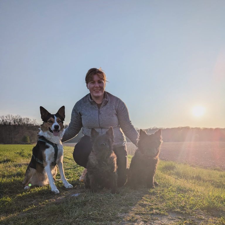 Tierphysiotherapeutin Andrea Knoll mit ihren Hunden mit Blick auf einen See, im Hintergrund sieht man die Berge